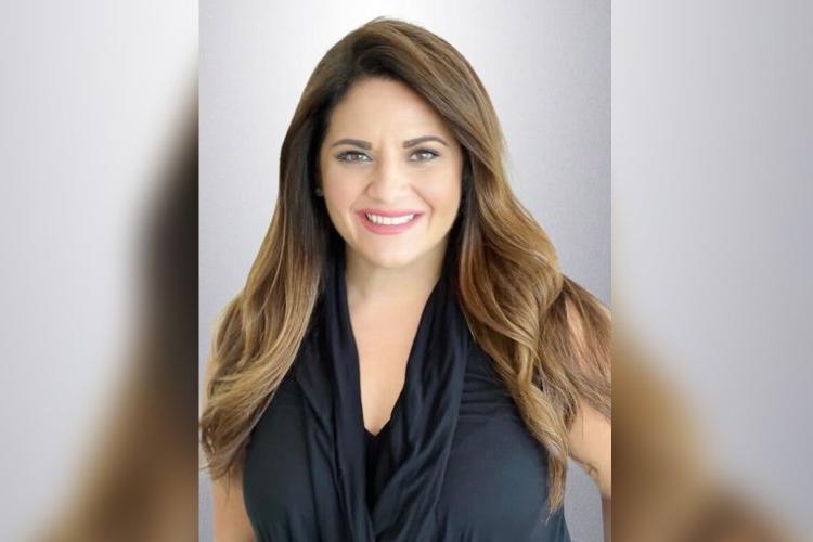 Angela Grande '05 in black dress against a gray background. 